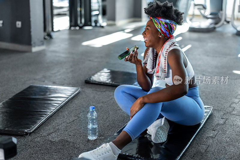 An African woman is resting after a hard exercise in a gym.